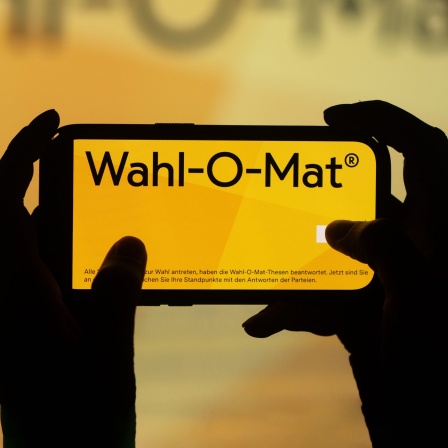 Zwei Hände halten ein Handy mit dem Wahl-O-Mat-Logo auf dem Bildschirm