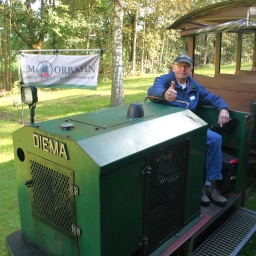 Ein Mann sitzt auf einer kleinen grünen Eisenbahn, der Moorbahn.