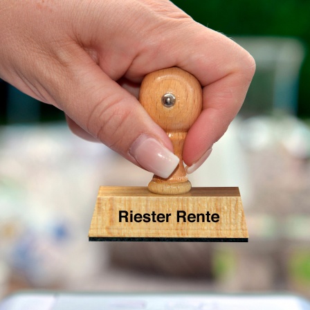 Frauenhand mit Stempel mit der Aufschrift Riester Rente 