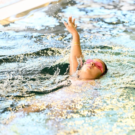 Ein Kind schwimmt auf dem Rücken im Schwimmbad. 