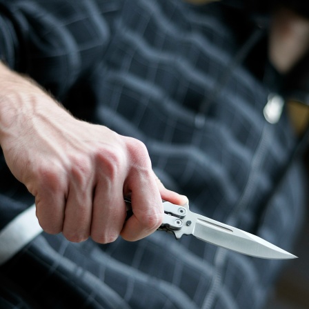 Ein junger Mann hält ein Messer in der Hand