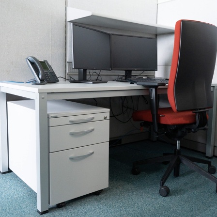 Ein leerer Schreibtisch steht in einem Großraumbüro.