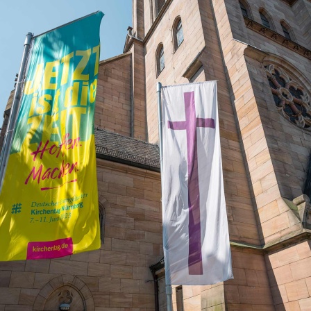 Eine Fahne des Deutschen Evangelischen Kirchentags und die Kirchenfahne der Evangelischen Kirche hängen vor der St. Paul Kirche in Nürnberg.