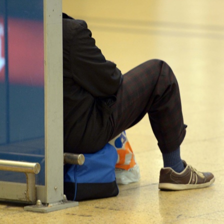 Symbolfoto: Eine Person sitzt wartend auf dem Boden eines Bahnhofs (Streik 2014)
