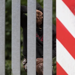 Das Bild zeigt eine äthiopische Frau hinter dem Grenzzaun zwischen Belarus und Polen.