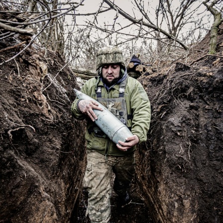 Ein Soldat an der Front in Donezk trägt schwere Munition durch einen Schützengraben.