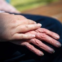 Die Hand einer Pflegefachkraft liegt auf der Hand einer Bewohnerin des Seniorenheims. (Bild: dpa)