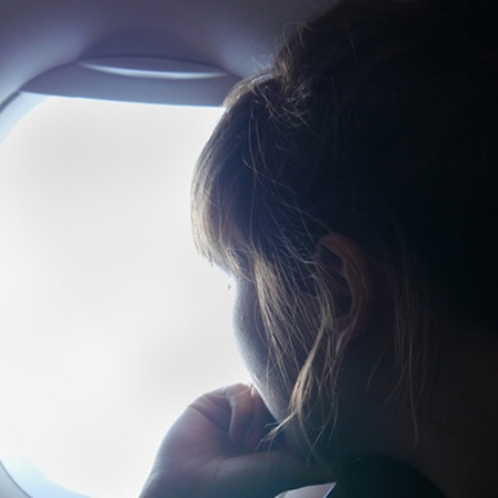 Eine Frau schaut aus dem Fenster eines Flugzeugs.