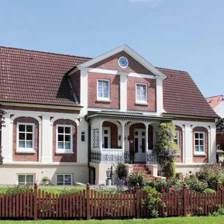 Ein Einfamilienhaus mit Veranda und einem Garten (Symbolbild)