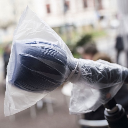 Ein Mikrofon, das mit einer Plastiktüte vor Viren geschützt wird