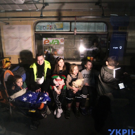 Kinder sitzen in einer Metrostation, die als Luftschutzbunke dient.