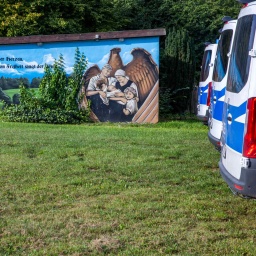 Einsatzfahrzeuge der Polizei stehen bei einer Durchsuchungsaktion vor einem polizeibekannten Grundstück.