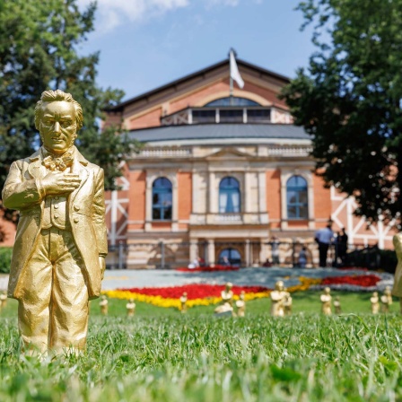 Goldfarbene Wagner-Figuren des Konzeptkünstler Ottmar Hörl stehen im Rahmen der Kunstinstallation "Verneigung" vor dem Festspielhaus vor Beginn der Bayreuther Festspiele.