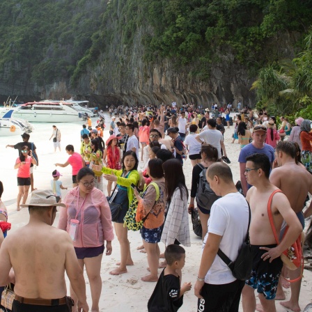 Eine große Anzahl von Touristen an einem weißen Sandstrand.