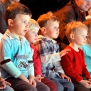 Symbolfoto: Nebeneinander sitzende Kinder verfolgen gebannt die Probe eines Theaterstücks.