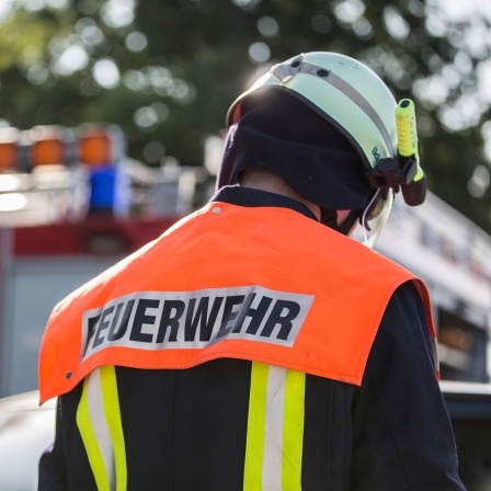 Das Beitragsbild des Dok5 "Notfall Feuerwehr" zeigt einen Feuerwehrmann von hinten mit gesenktem kopf.