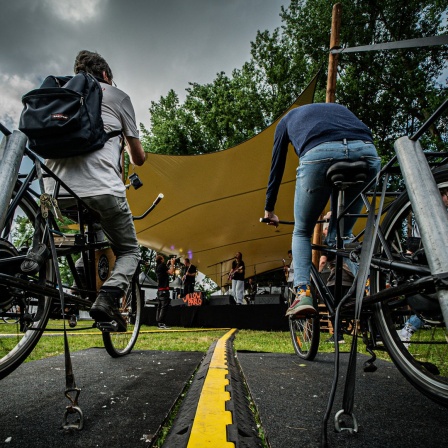 Beim Futur 2 Festival in Hamburg strampeln Besucher vor einer Bühne auf Fahrrädern, um Strom zu erzeugen.