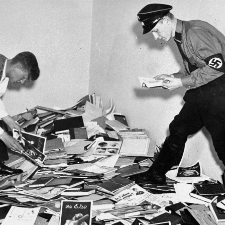 Ein NS-SA-Mitglied und ein Student untersuchen Materialien, die aus der Bibliothek von Dr. Magnus Hirschfeld geplündert wurden.