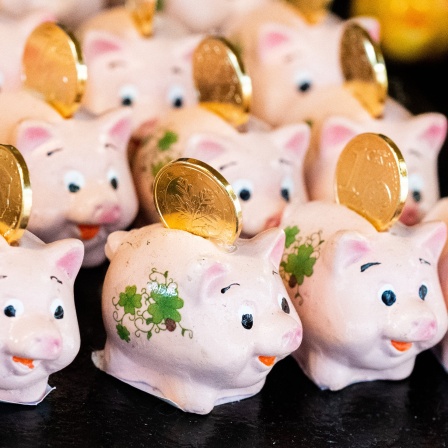 Kleine Schweinchen mit Geldmünzen sind auf einem Stand zum Verkauf für Silvester und Neujahr aufgestellt. Sie sollen Glück, Wohlstand und Reichtum bringen.