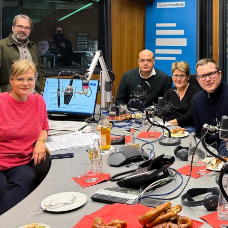 Nadine Lindner, Stephan Detjen (Deutschlandfunk), Robin Alexander (WELT), Sabine am Orde (taz), Ulf Buermeyer (Lage der Nation), Peter Dausend (ZEIT) und Katharina Hamberger (Deutschlandfunk) sitzen an einem Studiotisch unseres Hauptstadtstudios.