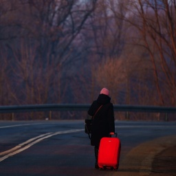Eine Frau, die vor dem Krieg in der Ukraine geflohen ist, geht mit ihrem Gepäck an der ukrainisch-polnischen Grenze in Kroscienko.