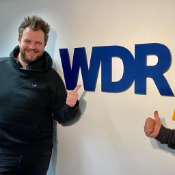 Paveier (Sven Welter, l., und Detlef Vorholt, r.) vor WDR 4 Logowand
