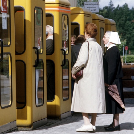 Sechs gelbe Telefonzellen der Deutschen Bundespost mit davor wartenden Kunden 1985