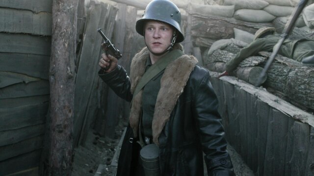Ein Soldat mit Stahlhelm und Waffe im Schützengraben.