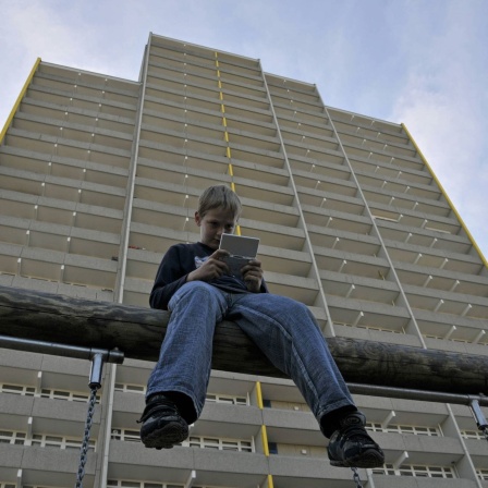 Junge spielt mit seinem Nintendo vor einem Hochhaus