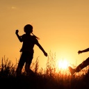 Drei Kinder spielen fröhlich im Sonnenuntergang. 