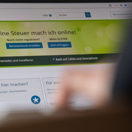 Eine Person sitzt vor einem Laptop und blickt auf die Startseite des &#034;Elster&#034;-Portals.