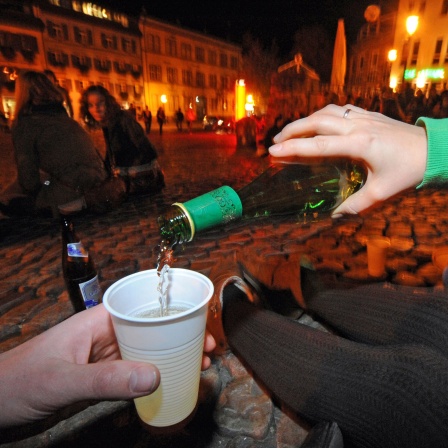 Jugendliche sitzen auf dem Augustinerplatz in der Innenstadt von Freiburg und trinken Alkohol.