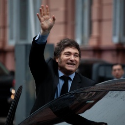 Der argentinische Präsident Javier Milei winkt in Richtung Kameras beim Einsteigen in ein Auto. Buenos Aires, Argentinien, 2024.