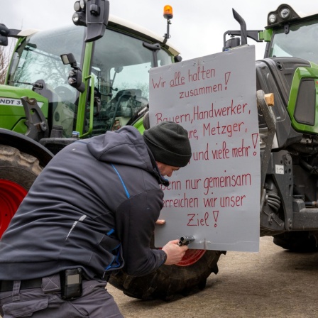 Ein Mann befestigt ein Protestschild an einem Schlepper.