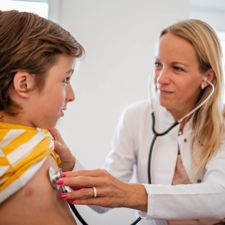 Ärztin untersucht Kind mit Stethoskop