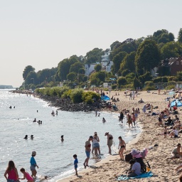 Menschen genießen die Sonne und das Wasser am Elbstrand von Oevelgönne.