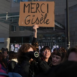 Eine Frau hält ein Plakat mit dem Schriftzug "Merci Gisèle" in die Höhe. 