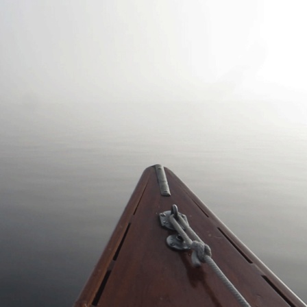 Spitze eines kleinen Bootes, das bei Nebel auf einem See treibt.