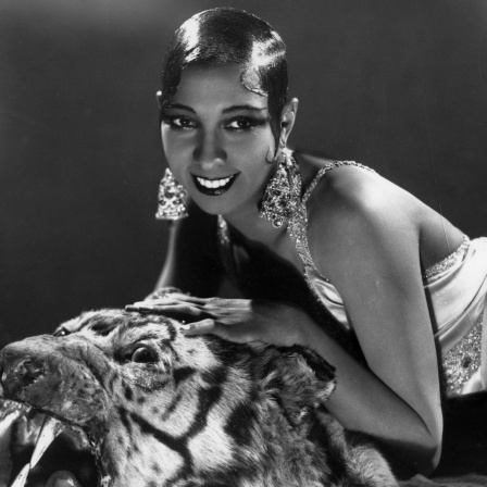 Josephine Baker lehnt auf einem Tigerkopf und lächelt in die Kamera.