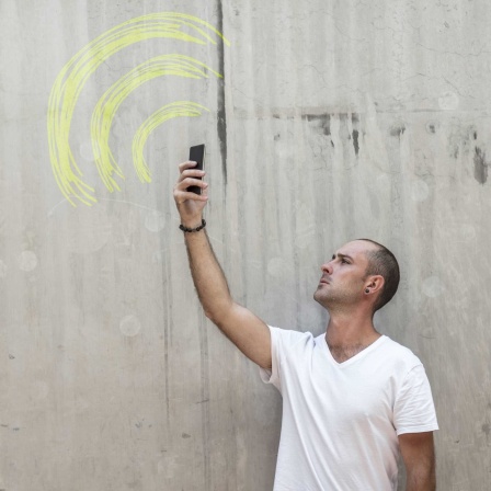 Symbolbild: Ein Mensch hält ein Smatphone auf der Suche nach einer guten Verbindung nach oben.