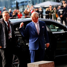 King Charles gestikulierend vor einer Limousine vor dem Berliner Hauptbahnhof.