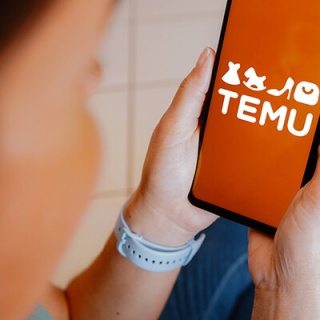 Ein Mensch hält ein Handy in der Hand auf dem die Temu-App geöffnet ist