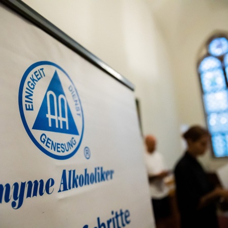 «Anonyme Alkoholiker» steht auf einem Aufsteller in einer Kirche. Auf dem Logo darüber steht "Einigkeit, Dienst, Genesung".