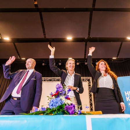 Robert Lambrou (l-r, AfD), AfD-Landesvorsitzender/Spitzenkandidat zur Landtagswahl, Alice Weidel (AfD), Bundesparteivorsitzende, und Mariana Harder-Kühnel (AfD), eine von drei stellvertretenden Bundessprechern ihrer Partei, stehen winkend und lachend auf dem Podium zusammen. 