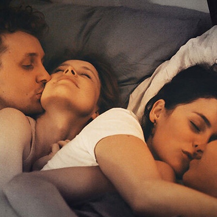 Vier Menschen liegen küssend im Bett