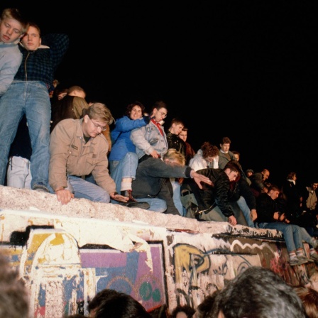 Menschen klettern auf die Mauer. Berlin, 09.11.1989