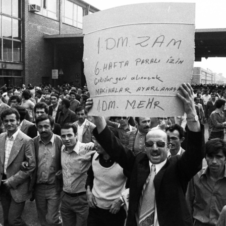 Der Streik bei den Ford-Werken, hier am 27. bis 29. 8. 1973 in Köln, war ein Spontanstreik, also ein wilder Streik. Die Serie von Streiks wurde u. von türkischen Migranten organisiert. Ursache war u. a. die starke Inflation. Auf dem Schild in türkischer Sprache, das einer der Männer in die Höhe hält, steht in der letzten Zeile auf Deutsch &#034;1 DM mehr&#034;.
