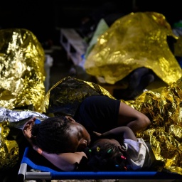 Eine Frau und ein Kind schlafen vor dem Aufnahmezentrum für Migranten. Der Stadtrat der italienischen Mittelmeerinsel Lampedusa hat angesichts Tausender neu angekommener Bootsmigranten den Notstand ausgerufen.