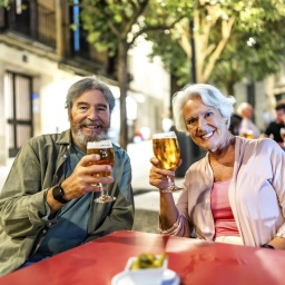 Foto eines älteren Paares, das Tapas und Bier genießt