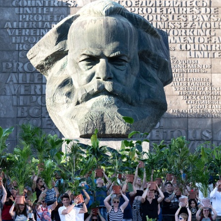 Menschen tragen jeweils eine Zimmerpflanze durch die Straßen von Chemnitz - vor dem Karl-Marx-Monument, dem Wahrzeichen der Stadt